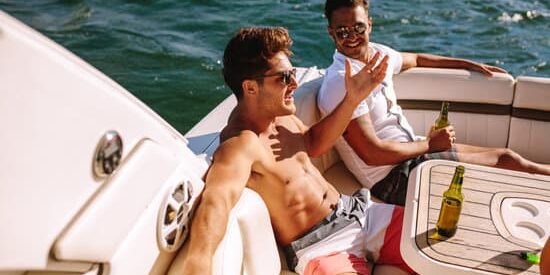 Young men sitting in a boat and having party. Male friends partying in a yacht.